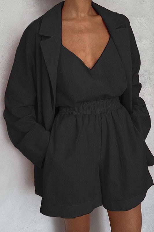 A person wearing a black crop top, matching shorts, and a blazer with a matching orange belt.