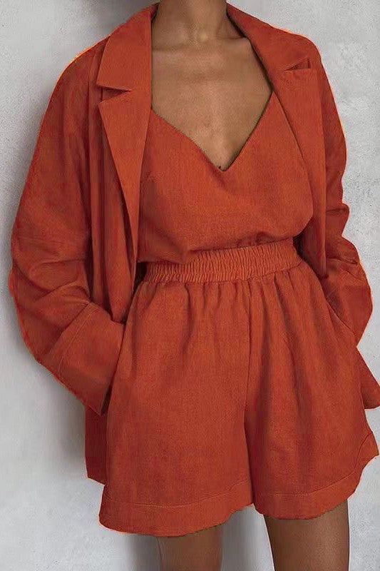 A person wearing an orange crop top, matching shorts, and a blazer with a matching orange belt.