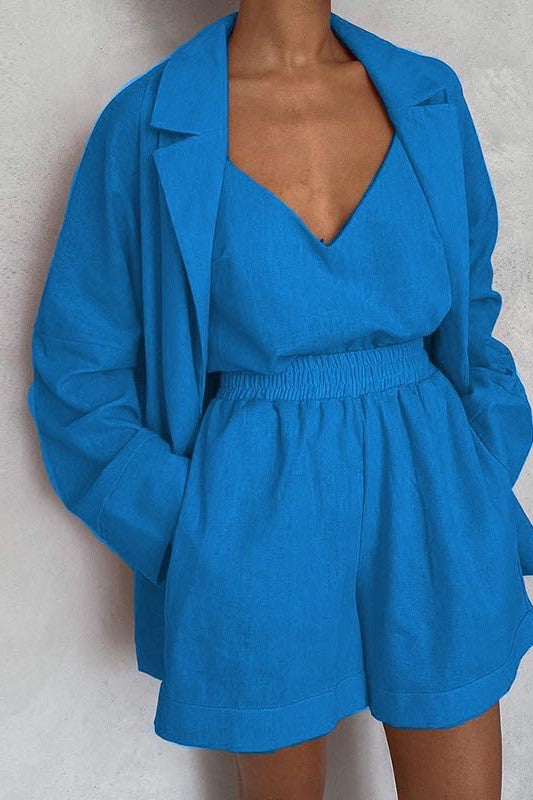 A person wearing an blue crop top, matching shorts, and a blazer with a matching orange belt.