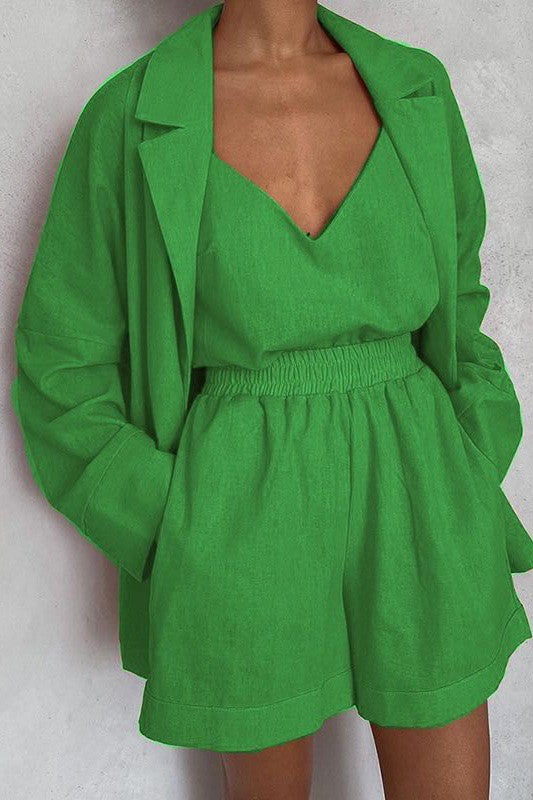 A person wearing a green crop top, matching shorts, and a blazer with a matching orange belt.