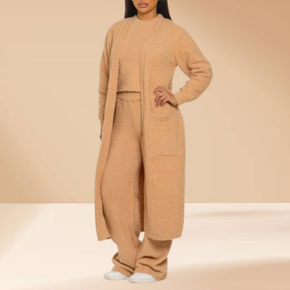 Person wearing a beige long coat and pants set on a beige background